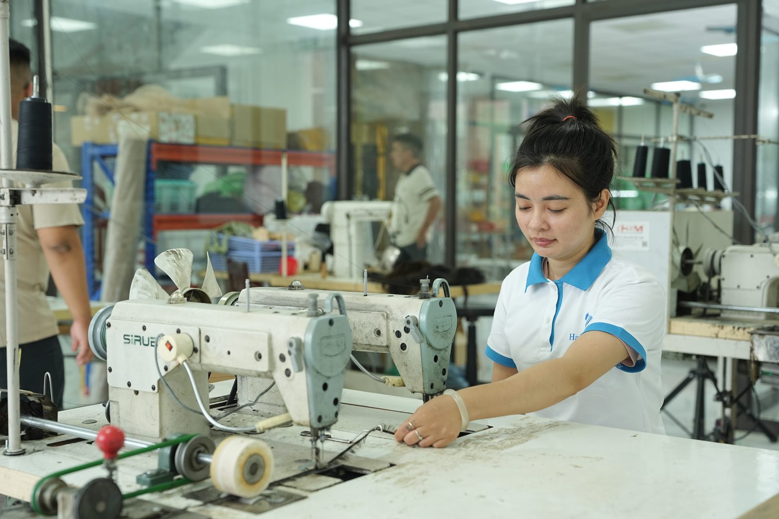 A woman at an industrial sewing machine in the factory sewing area