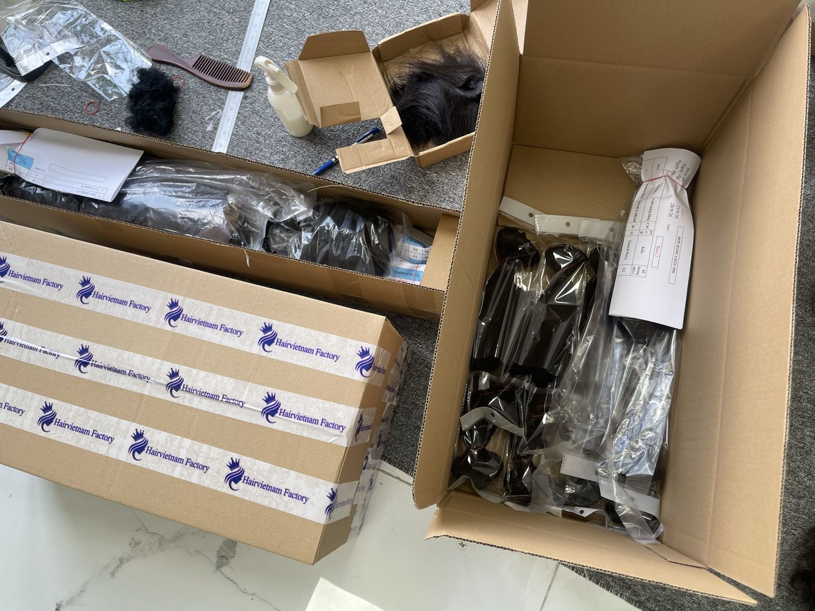 Bagged hair bundles packed in a carton next to boxes sealed with Hairvietnam Factory tape