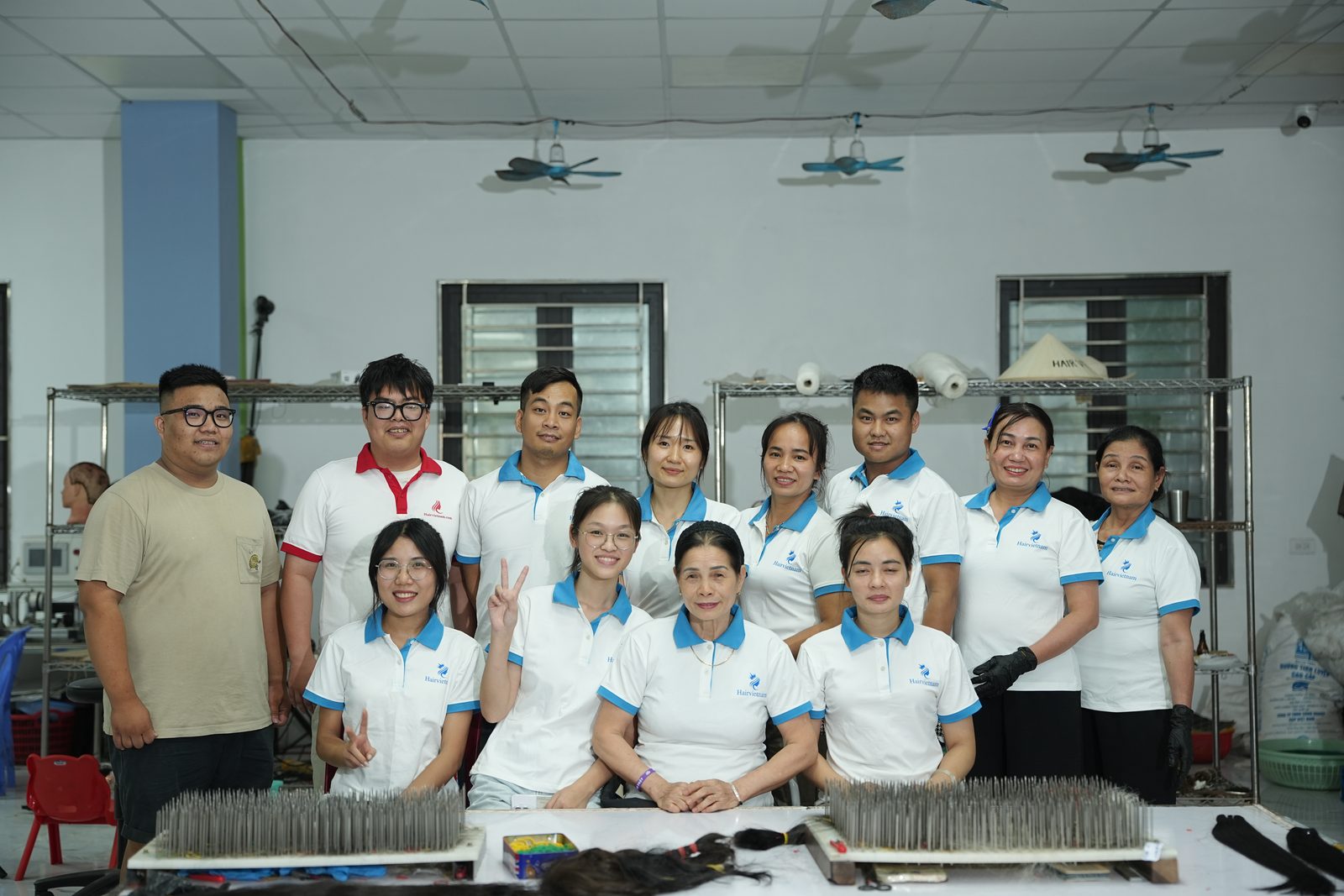Group photo of about twelve factory staff in white polo shirts standing behind a table