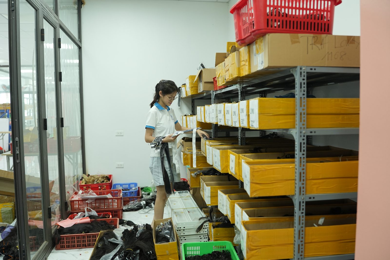 A staff member checks labeled cartons on storeroom shelves