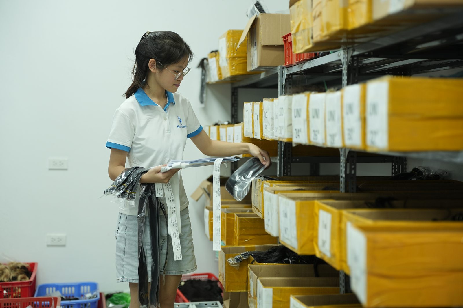 A staff member holds paperwork in front of storeroom shelves of labeled cartons